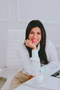 Portrait of a smiling young woman sitting at home