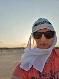 Portrait of man wearing sunglasses and headscarf against sky during sunset