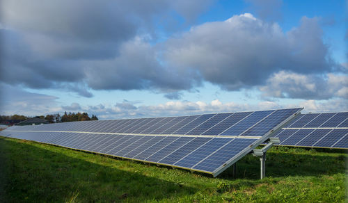 Scenic view solar panel farm on field against sky, germany