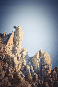 Rock formations by sea against clear sky