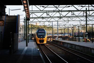 Train at railroad station in city against sky