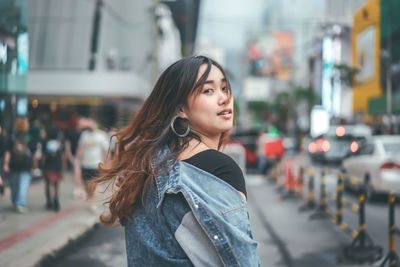 Portrait of young woman standing on street in city