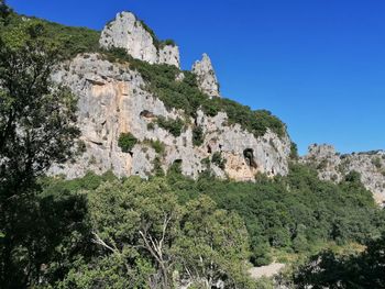 Low angle view of rocks against clear blue sky