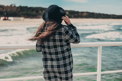 Rear view of woman standing against sea