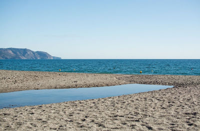 Scenic view of beach against clear blue sky