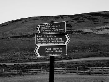 Information sign on grassy field against sky