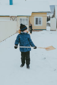 Boy cleans snow with a shovel on the street. a boy clears the road from snow in winter.