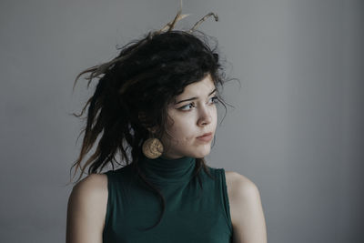 Portrait of beautiful young woman standing against gray background