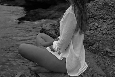 Low section of woman sitting at beach