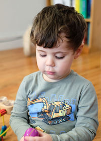 Portrait of a young boy of three playing with a toy in the living room