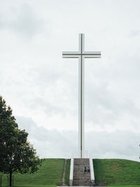 Cross on field against sky