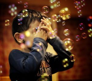 Close-up of boy amidst bubbles in mid-air at night