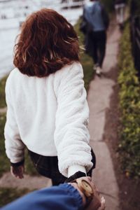 Cropped image of man holding girlfriend hand on footpath