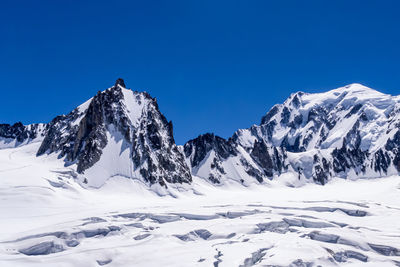 Scenic view of snowcapped mountains against clear blue sky
