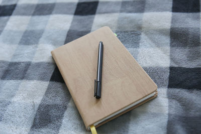 High angle view of pen and note pad on tablecloth