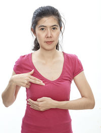 Woman touching breast while standing against white background