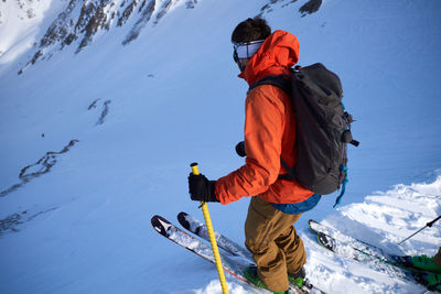 Man with umbrella on snowcapped mountain during winter