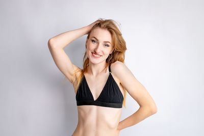 Portrait of young woman standing against white background