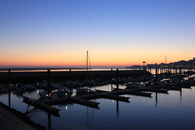 Boats moored in harbor at sunset