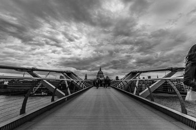 View of people walking on bridge under cloudy sky