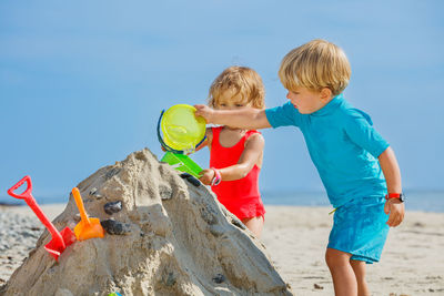 Rear view of mother and daughter standing at beach