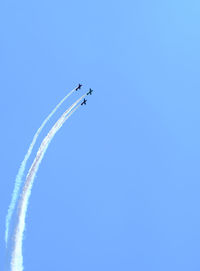 Low angle view of airplane flying against clear blue sky