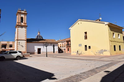 Street amidst buildings against clear blue sky