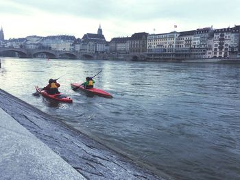 People rowing boat in river against sky