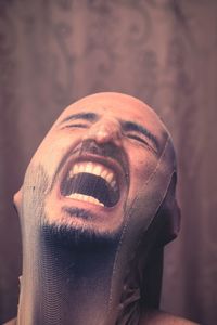 Close-up of man shouting while wearing fabric on face