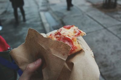 Close-up of hand holding pizza slice