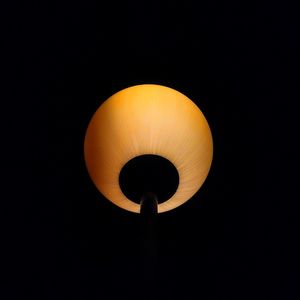 Low angle view of illuminated light bulb against black background