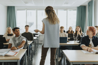 Rare view of teacher explaining male and female students in classroom at high school