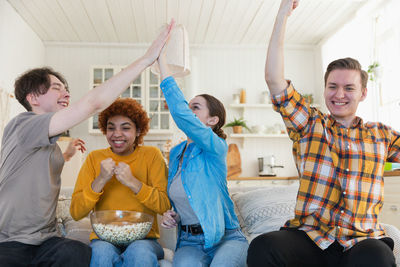 Friends using digital tablet while sitting on sofa at home