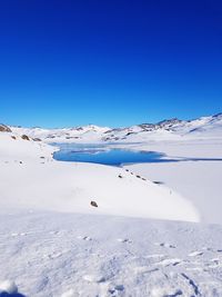 Scenic view of snow covered mountains against clear blue sky