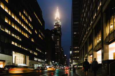 Illuminated city street against sky at night