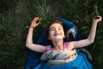 Cute girl in sleeping bag on field