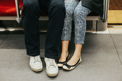 Closeup of man and woman legs in outdoor shoes together. couple dating sitting on seats in subway