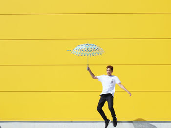 Full length of a man standing against yellow wall