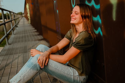 Young woman sitting on railing