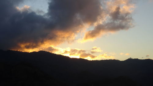 Scenic view of silhouette mountains against dramatic sky