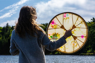 Rear view of woman holding umbrella against sky