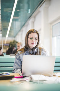 Serious female student using laptop in cafeteria