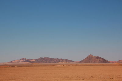 Scenic view of desert against clear blue sky