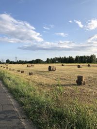 Hay bales on field against sky