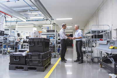 Two businessmen shaking hands in factory hall