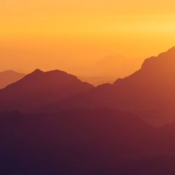 Scenic view of silhouette mountains against romantic sky at sunset