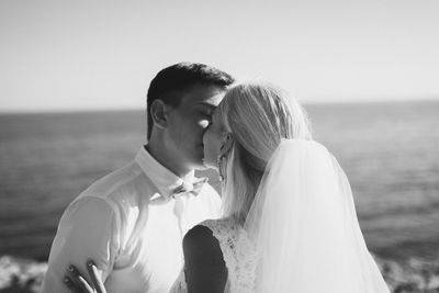 Bride and groom kissing against clear sky