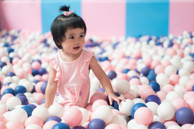 Cute baby girl standing in ball pool
