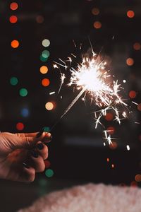 Cropped hand holding illuminated sparkler