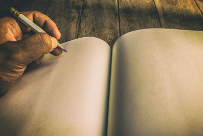 Cropped hand of man writing in blank book